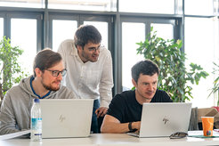 Marcus Ossiander leaning over two people with laptops